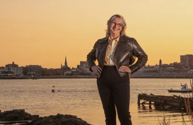 Karen Houseknecht standing infront of Casco Bay and the city of Portland